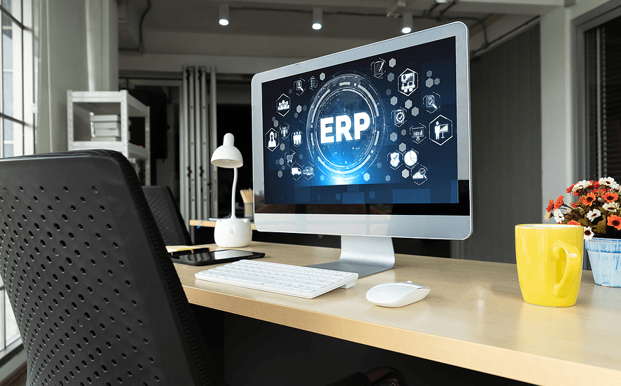 desk with computer on it. monitor shows ERP accounting software