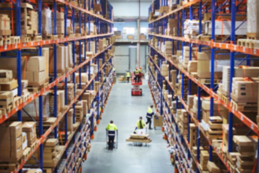Blur warehouse background. Above view of warehouse workers moving goods and counting stock in aisle between rows of tall shelves full of packed boxes