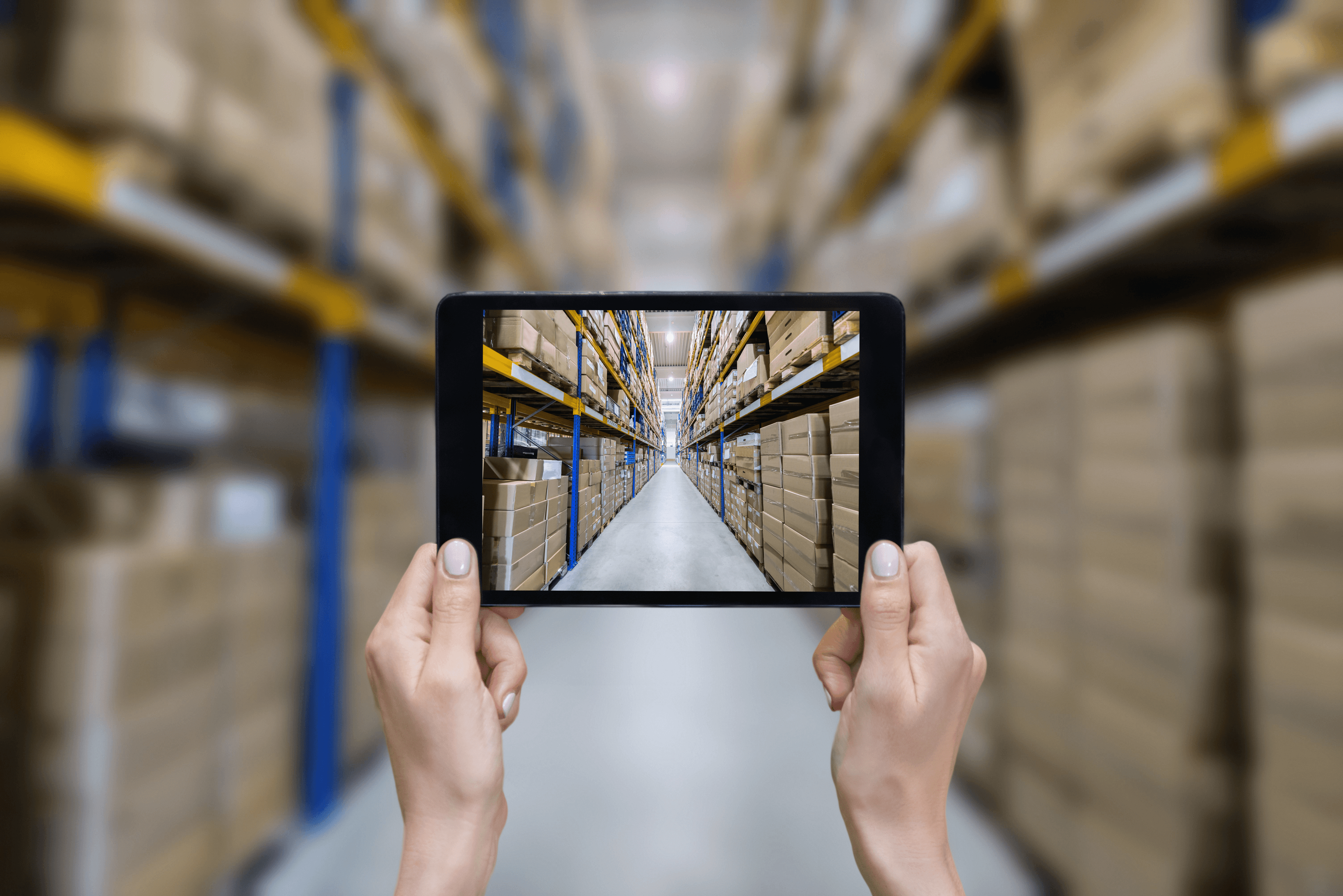 Hands hold up a tablet looking down the alley of a warehouse