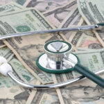 Medical stethoscope on a pile of money signifying the relationship of money and medicine